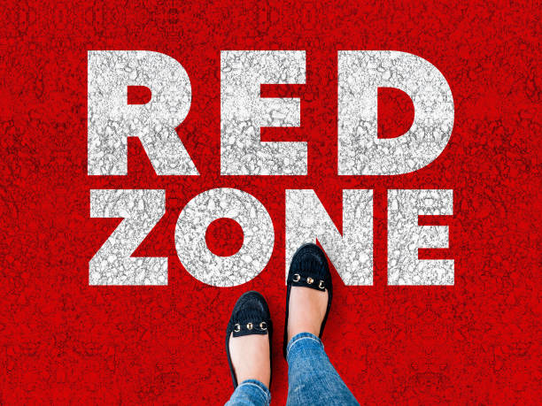 woman legs in black shoes standing on red asphalt with words Red Zone